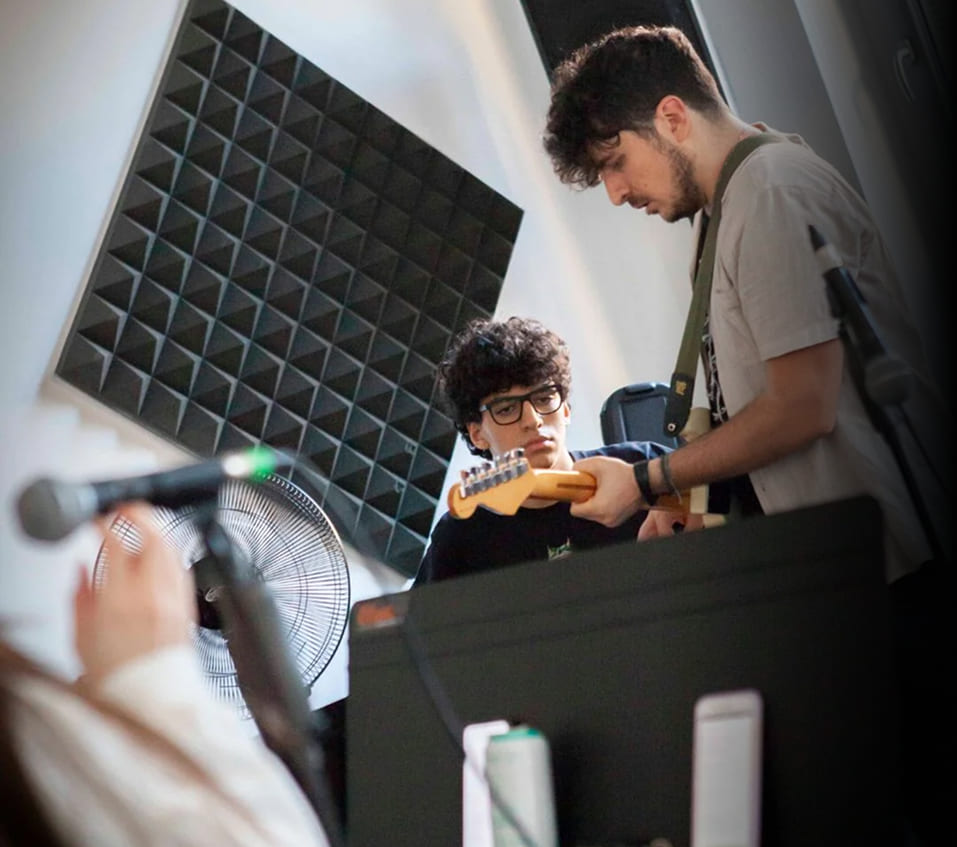 Studente della Scuola e Accademia di Musica Cluster osserva attentamente il docente durante una lezione individuale di chitarra elettrica in un’aula insonorizzata