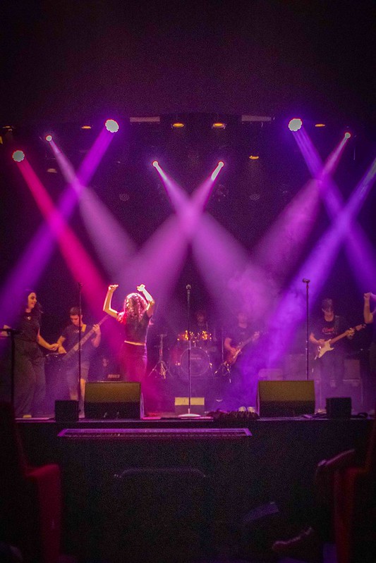 Concerto live della Scuola di Musica Cluster con studentessa cantante e band di accompagnamento.