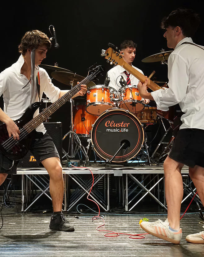 Band di studenti della Scuola di Musica Cluster in concerto con batteria, basso e chitarra sul palco.