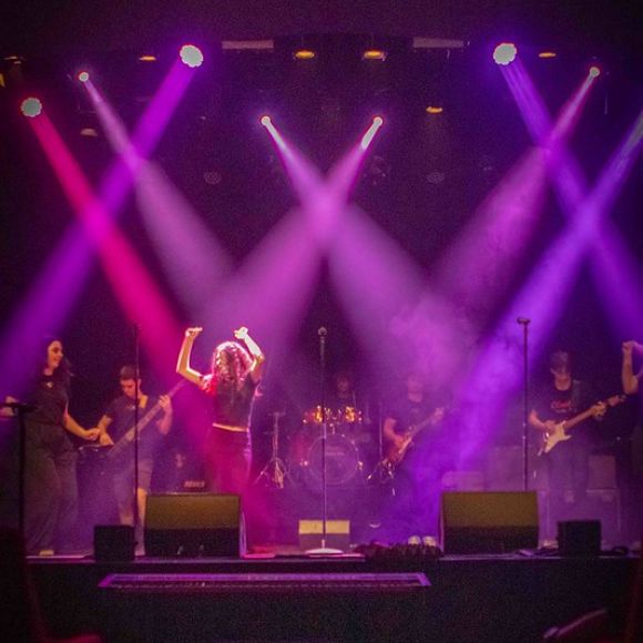 Concerto live della Scuola di Musica Cluster con studentessa cantante e band di accompagnamento.
