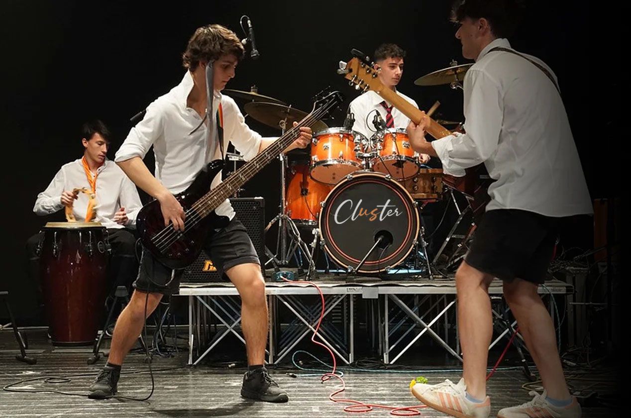 Lezione collettiva di Musica d'Insieme alla Scuola e Accademia di Musica Cluster con studenti che suonano chitarra elettrica, batteria e tastiera, accompagnati da un insegnante