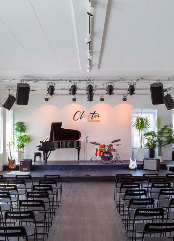 Auditorium della Scuola di Musica Cluster con pianoforte, batteria e sedie allestite per l’Open Day